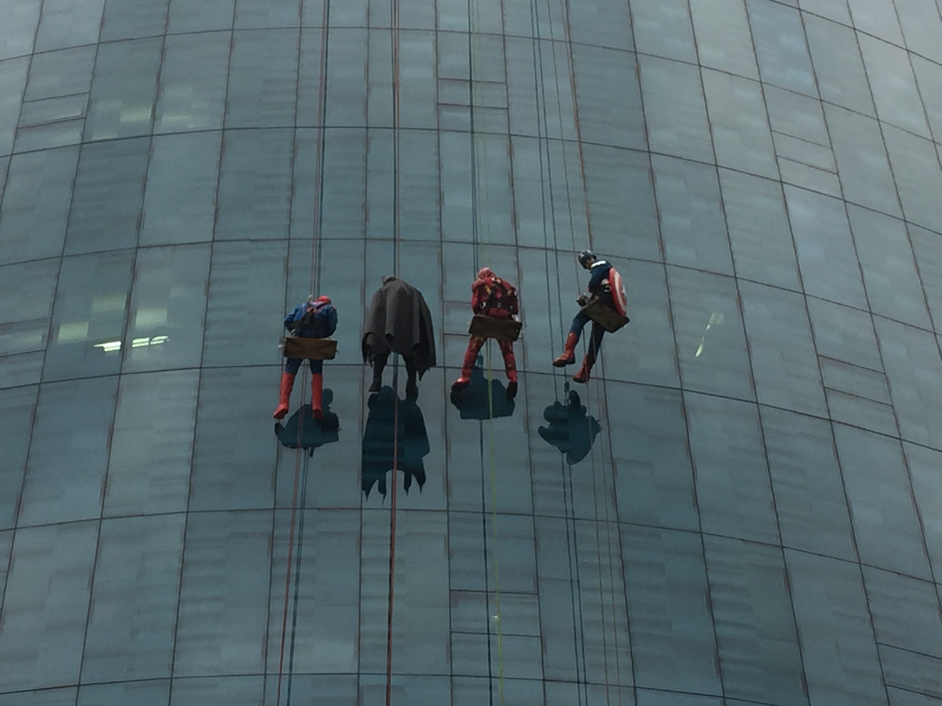 High rise window cleaners dressed as Superheroes rappel down the side of the hospital to surprise children on halloween